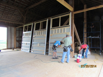 Installing barn doors during barn renovation on historical farming barn later turned into wedding venue in Virginia.